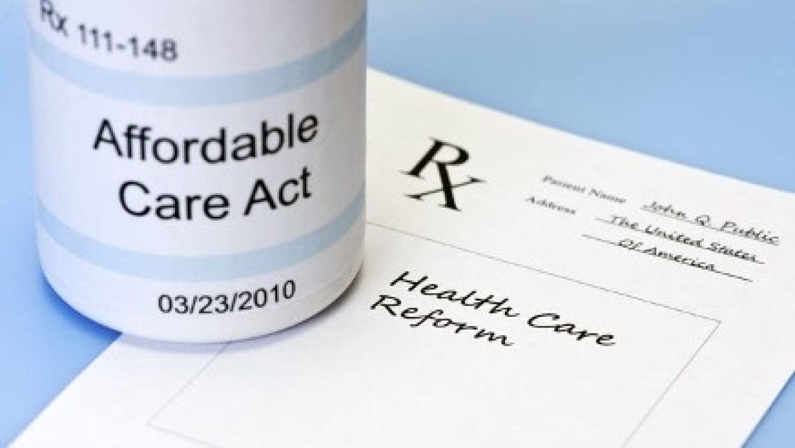 prescription bottle with the words affordable care act sits on top of a doctors prescription