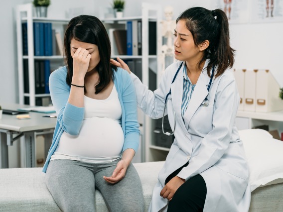 doctor consoling crying pregnant woman
