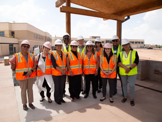 a group of people wearing hard hats and safety vests in front of a building site