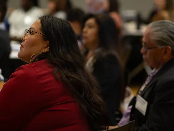 a woman wearing a red top listens to a speaker