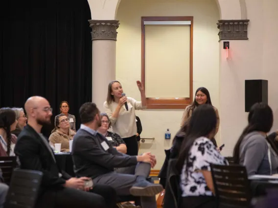 a woman stands to ask a question of a speaker