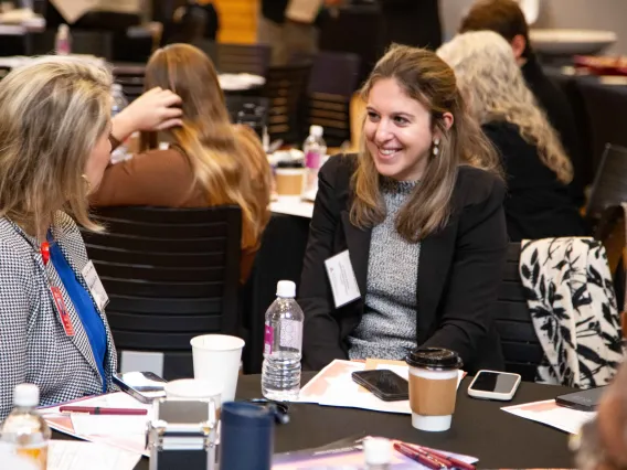 two women share a laugh while sitting at a table covered in a black table cloth