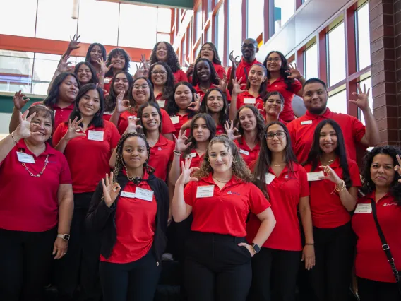 Group of students wearing red polo shirts making wildcat sign with their hands