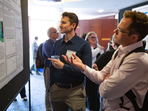 two men look at a poster presentation