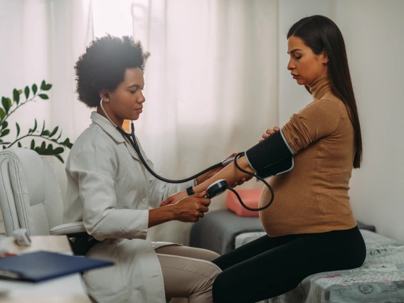 doctor taking blood pressure of pregnant woman