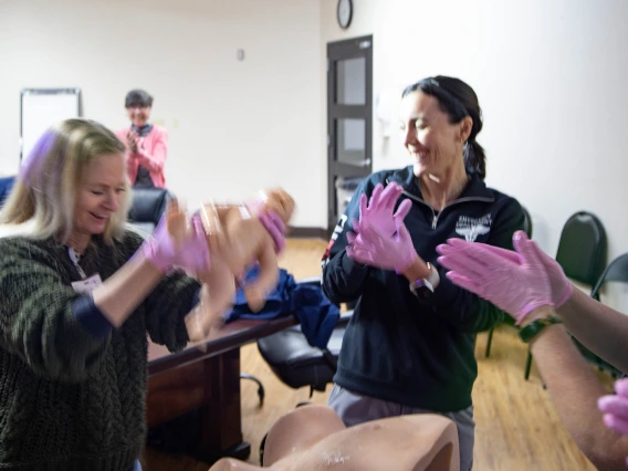 three women with pink gloves clapping