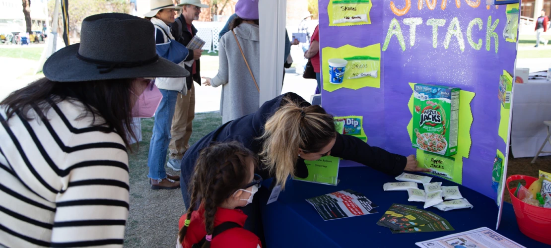 young woman points to a display of sugar in snacks with a mother and young daughter look at the display