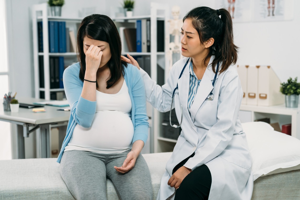 doctor consoling crying pregnant woman