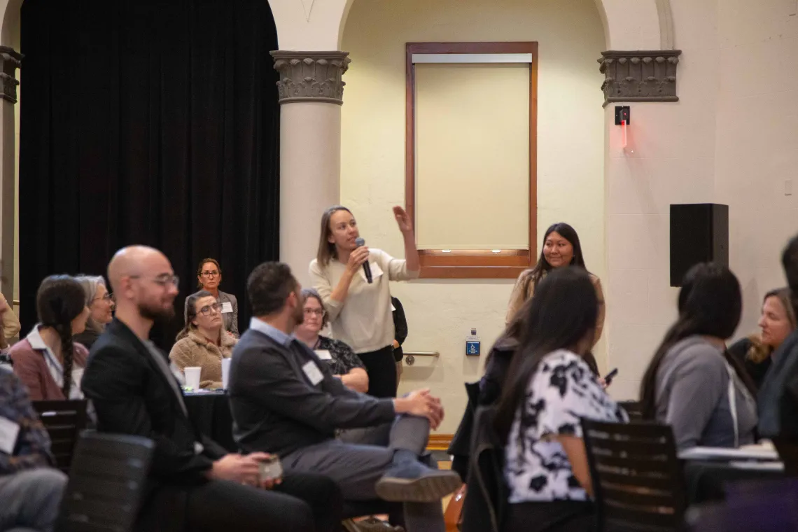 a woman stands to ask a question of a speaker