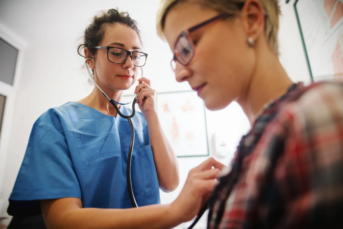 doctor listens to a patients heart with a stethoscope