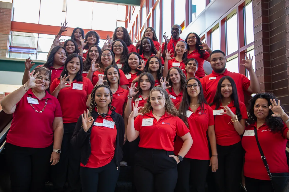 Group of students wearing red polo shirts making wildcat sign with their hands