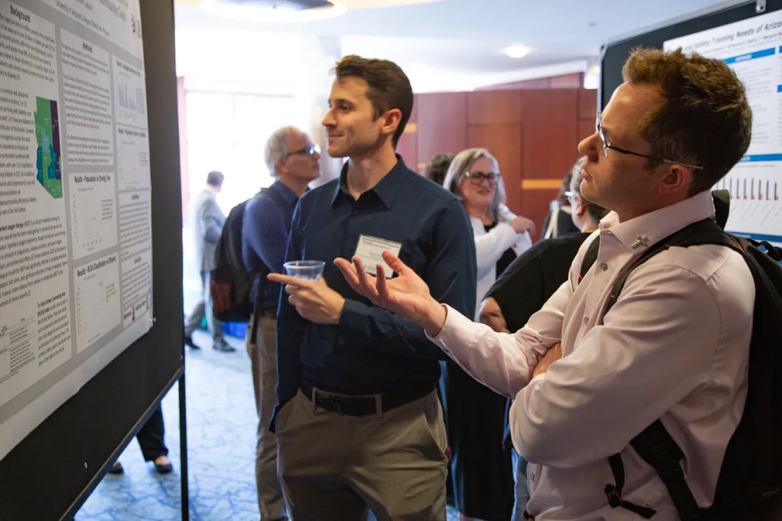 two men look at a poster presentation