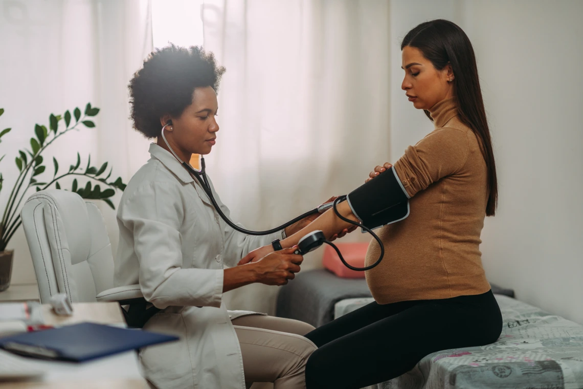 doctor taking pregnant persons blood pressure