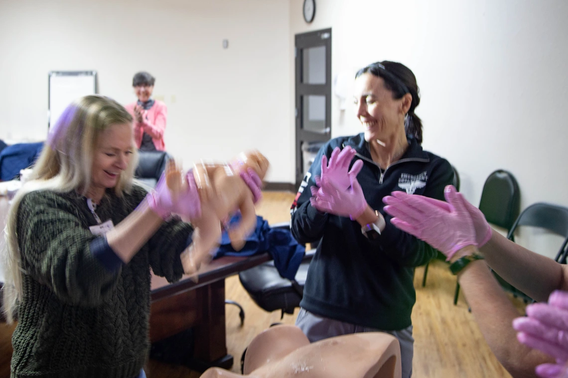 three women with pink gloves clapping