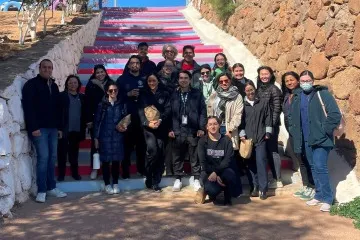 group of students gather in front of a mural