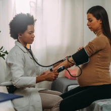 doctor taking pregnant persons blood pressure